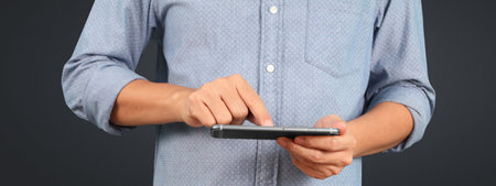 Man holding smartphone in hand device and touching screenの写真素材