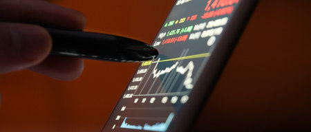 Hand touching mobile phone investing application. Stock market investment appの写真素材