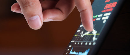 Hand touching mobile phone investing application. Stock market investment appの写真素材