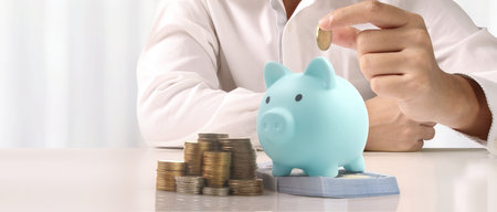 Man hand put coin money to piggy bank, saving and deposit money conceptの写真素材