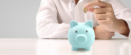 Man hand put coin money to piggy bank, saving and deposit money conceptの写真素材