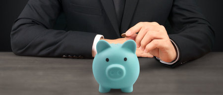 Man hand put coin money to piggy bank, saving and deposit money conceptの写真素材