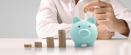 Man hand put coin money to piggy bank, saving and deposit money conceptの写真素材