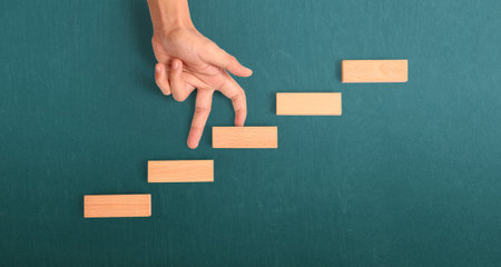 Hand liken person stepping up a toy staircase woodの写真素材