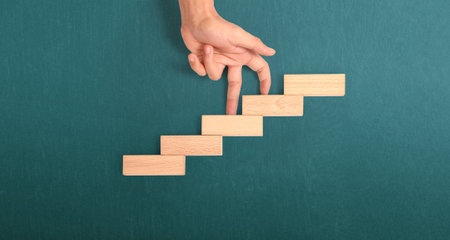 Hand liken person stepping up a toy staircase woodの写真素材