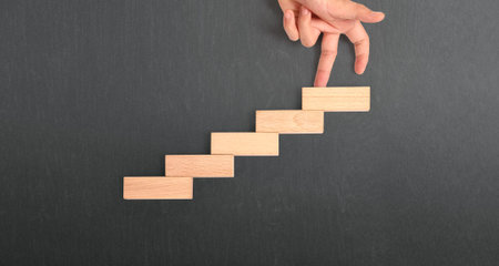 Hand liken person stepping up a toy staircase woodの写真素材