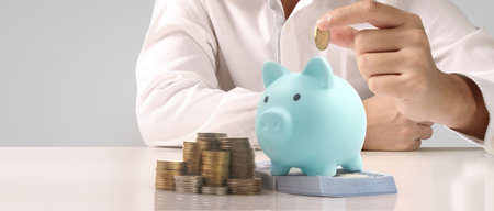 Man hand put coin money to piggy bank, saving and deposit money conceptの写真素材