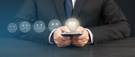 Man holding smartphone device and touching screen with five star rating feedback iconの写真素材