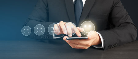 Man holding smartphone device and touching screen with five star rating feedback iconの写真素材