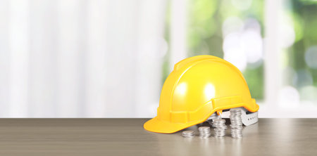 Yellow hardhat model house and coin with trading graph, financial investment concept