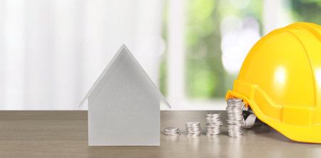 Yellow hardhat model house and coin with trading graph, financial investment conceptの写真素材