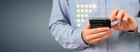 Man holding smartphone device and touching screen with five star rating feedback iconの写真素材