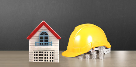 Yellow hardhat model house and coin with trading graph, financial investment conceptの写真素材