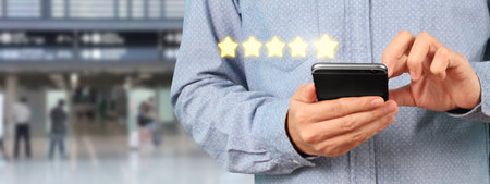 Man holding smartphone device and touching screen with five star rating feedback iconの写真素材