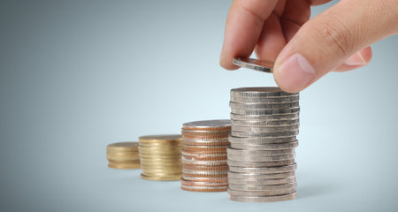 Hand laying coins on stacks coins in  rowの写真素材