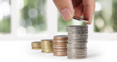 Hand laying coins on stacks coins in  rowの写真素材
