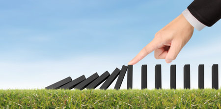 Hand stopping the Domino effect stopped by unique