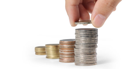 Hand laying coins on stacks coins in  rowの写真素材