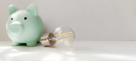 Saving money with a piggy bank and light bulb home office photo bright setting close-up financial awarenessの写真素材