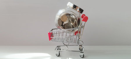 Shopping cart filled with coins financial planning business concept minimalist background close-up perspectiveの写真素材