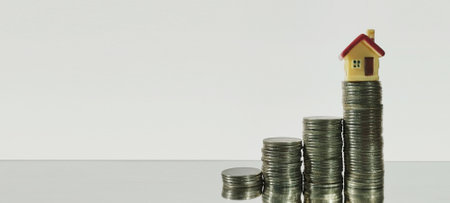 Investment growth house model on stacked coins financial concept studio setting minimalist viewpointの写真素材