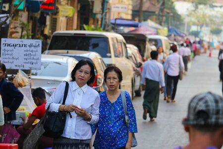 Yangon, Myanmar - February 1, 2019: Women in traditional burmese clothes walking down the streetのeditorial素材