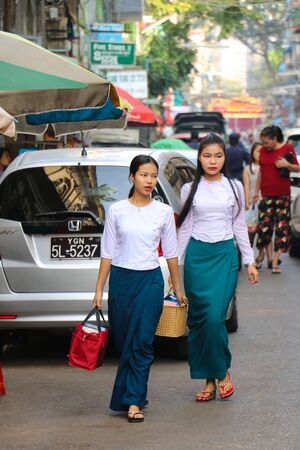 Yangon, Myanmar - February 1, 2019: Women in traditional burmese clothes walking down the streetのeditorial素材