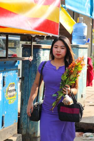 Yangon, Myanmar - February 1, 2019: Young and beautiful burmese woman with flowers walking down the streetのeditorial素材