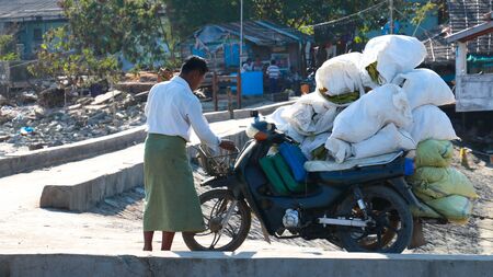 Ngapali, Myanmar - February 2, 2019: Burmese man carry cargo bags on his motorbikeのeditorial素材