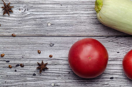 red juicy tomato top view on vintage wooden background with zucchini with place for an inscriptionの写真素材