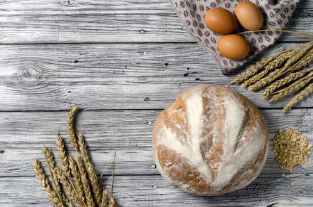homemade bread top view with ears of wheat on a wooden tableの写真素材