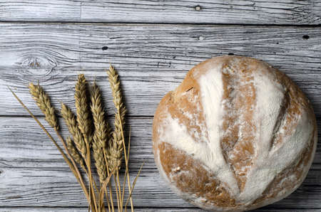 homemade bread top view with ears of wheat on a wooden tableの写真素材
