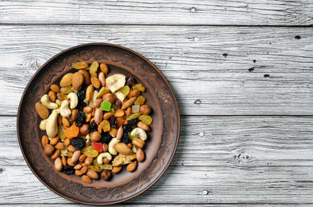set of dried fruits and nuts on a clay plate top view.の写真素材