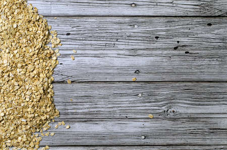 oatmeal scattered on a wooden table top view with a place for inscription.の写真素材