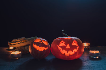 Halloween pumpkin head jack with candles lantern on a dark background with autumn leaves and corn horizontalの写真素材