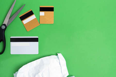 International Day for the Eradication of Poverty.Scissors cut credit card on a green background with crumpled paper on a green background.Flat layの写真素材