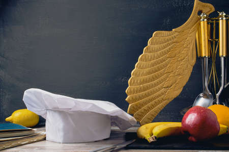 Cook hat,Chefs hat on a table with fruit carved board and dark background of free spaceの写真素材