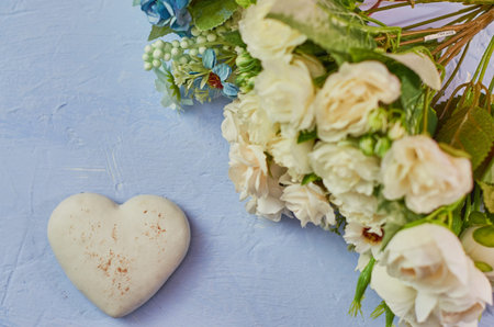 Kindness, love. Delicate blue background with white chocolate heart cookies and a bouquet of flowers...