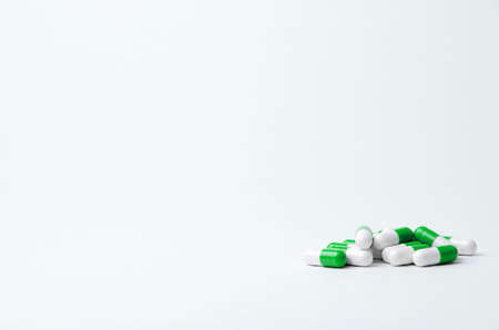 Green and white pills on a light background with place for text. Biological supplements, vitamins, medicines for health.の写真素材