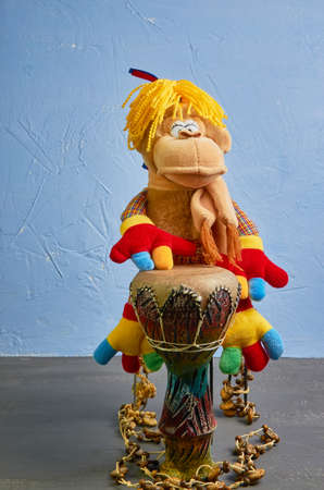 toy monkey with pigtails and colored paws plays the drum on a blue backgroundの写真素材