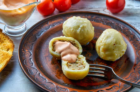 Khinkali is a national Georgian dish. On a clay plate with a sauceboat and cherry tomatoes in the background. Close-up. Horizontal.の写真素材