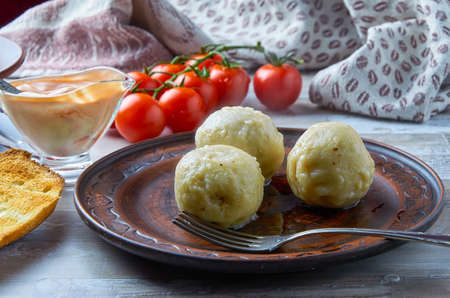 Khinkali is a national Georgian dish. On a clay plate with a sauceboat and cherry tomatoes in the background. Close-up. Horizontal.の写真素材