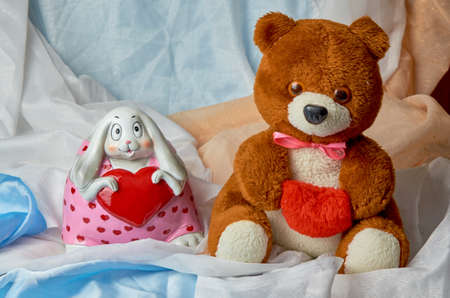 A teddy bear with a red heart in his hands, and a bunny with a heart in his hands on a colored holiday background with place for text. Valentine's Day. Postcard.8 Marchの写真素材