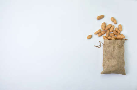 Nuts unpeeled peanuts spilled out of a linen bag on a white background close-up. place for text flat layの写真素材