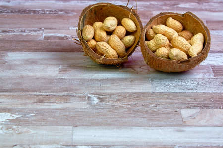 Peanuts lies in a coconut shell on a wooden table with place for text.Horizontalの写真素材