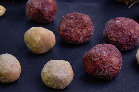 Raw food sweets made from peanuts, coconut and cocoa are on a black slate board.Close upの写真素材