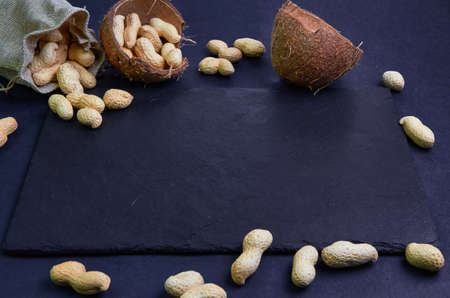 black empty slate board with scattered peanuts and coconut shell at the edges, space for text, copy space, front viewの写真素材