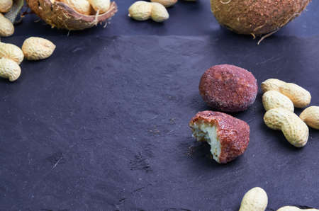 Raw food sweets made from peanuts, coconut and cocoa are on a black slate board.Copy spaceの写真素材