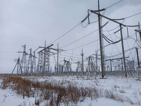 High voltage towers with wires in cloudy snowy weather with clouds in the skyの写真素材