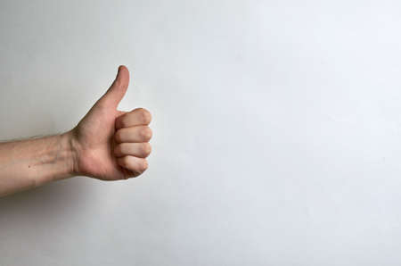 Thumb male left hand on a white background with place for text. Like, approval, cool, complimentの写真素材